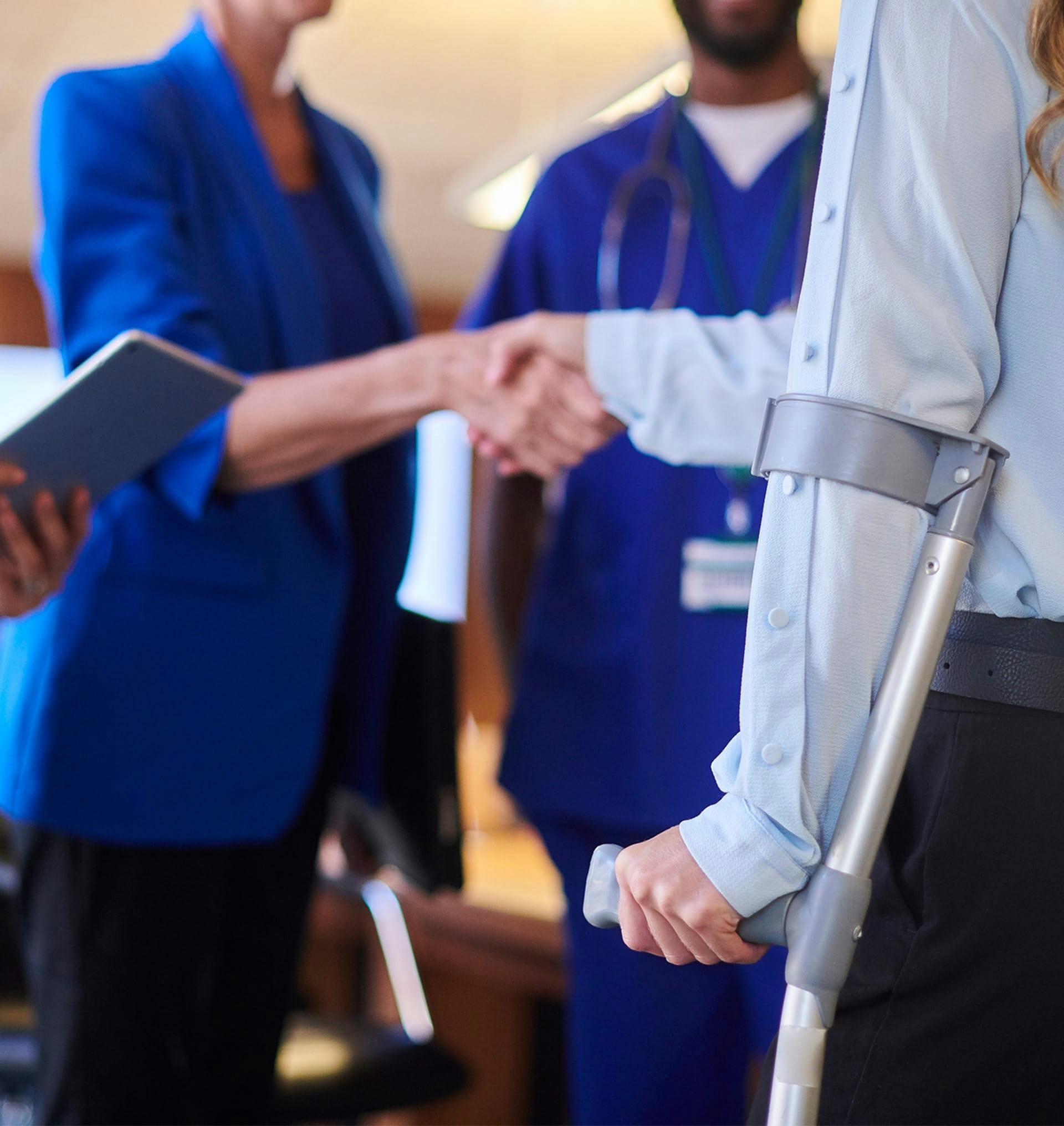 doctor shaking hands with woman on crutches