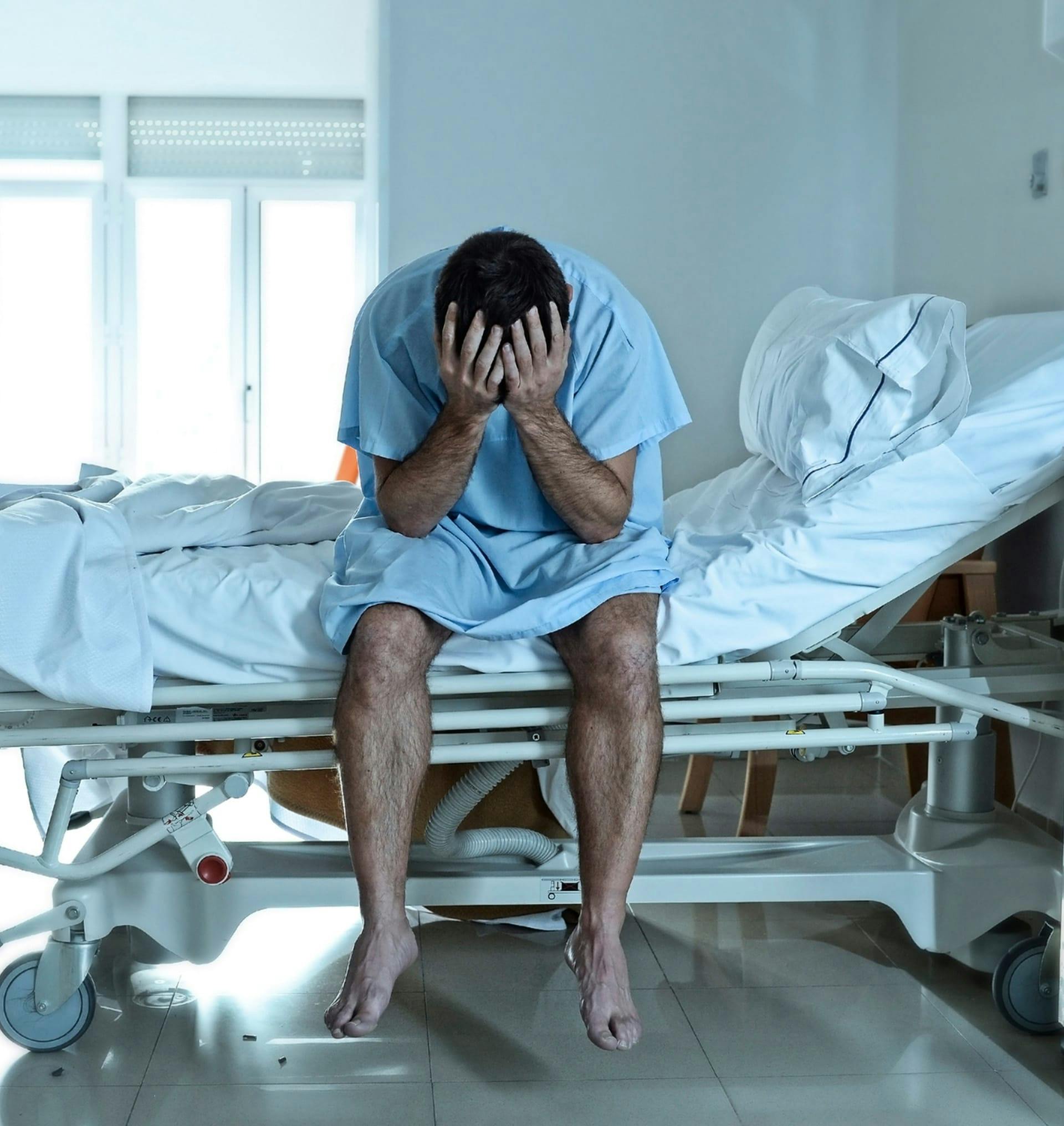distressed man sitting on hospital bed