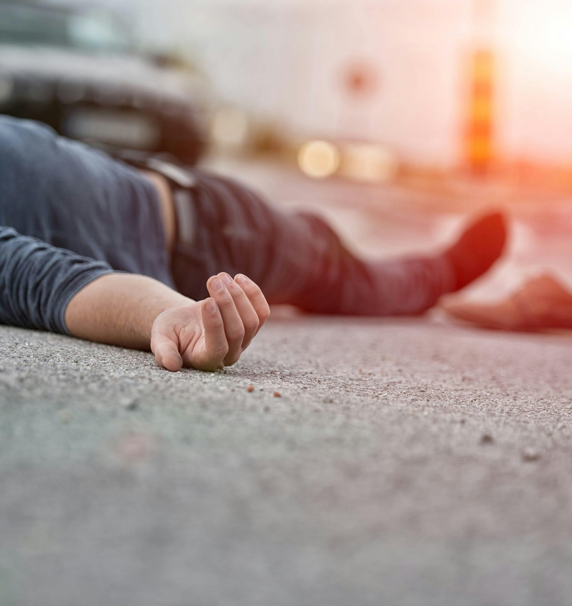 man laying on ground after car accident