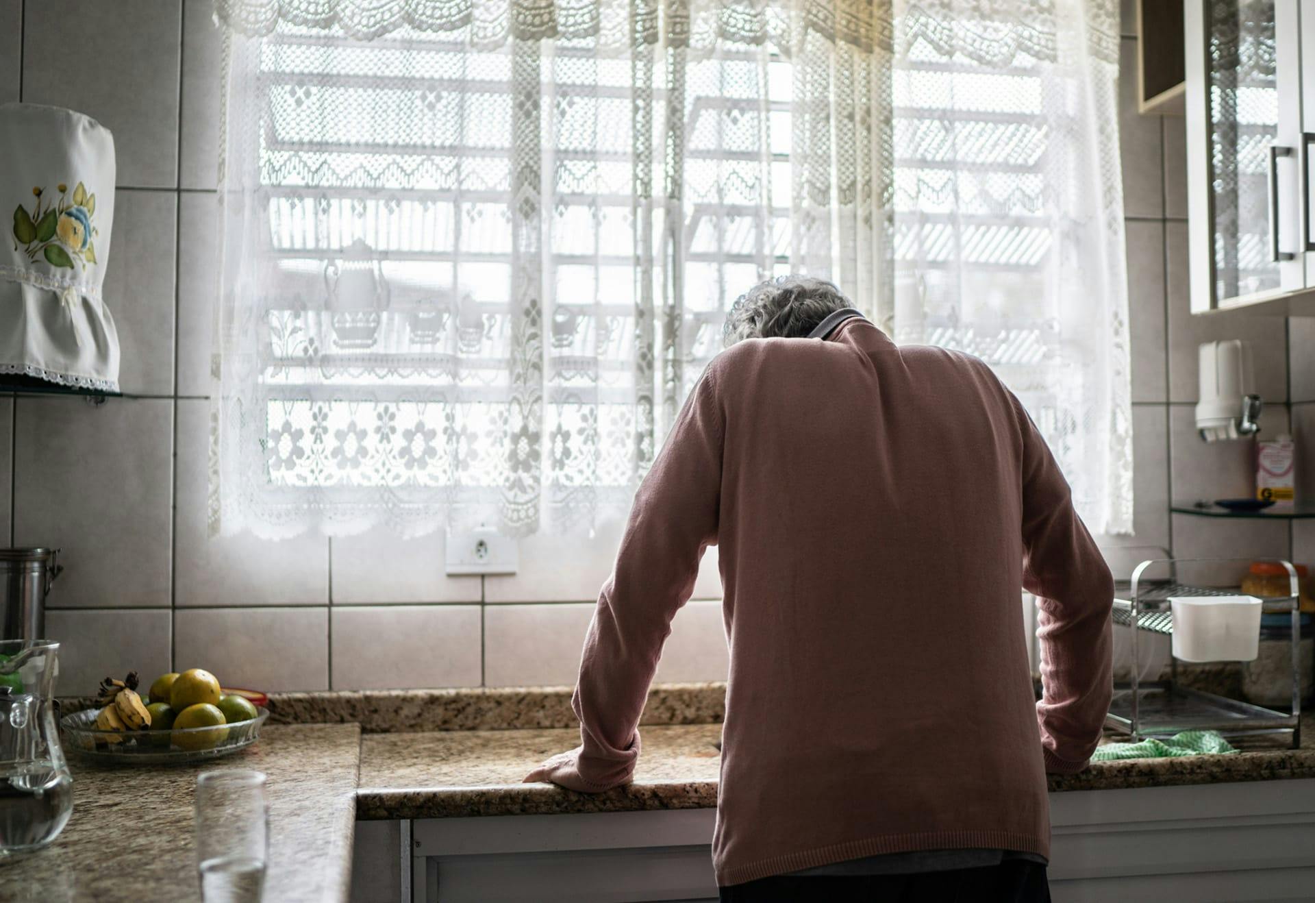 sorrowful person leaning against counter