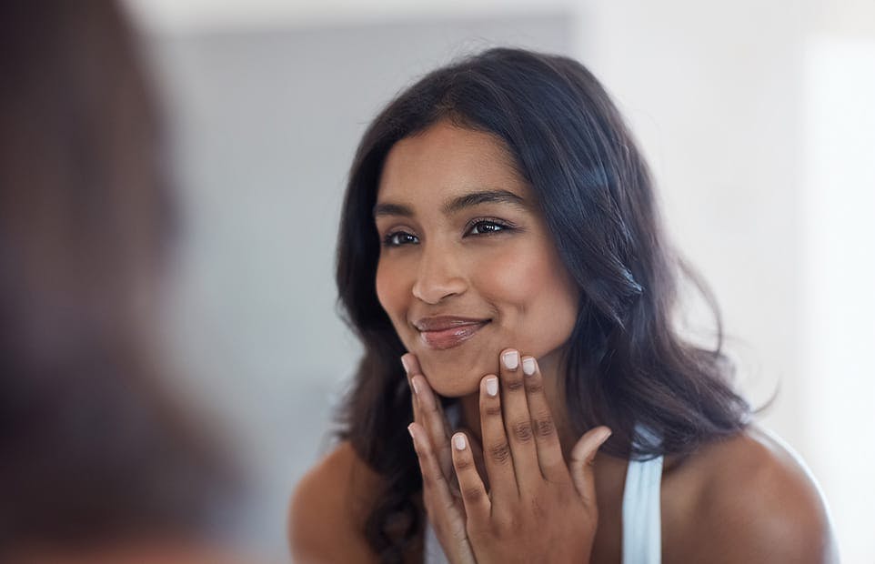 Woman touching her chin and looking in the mirror