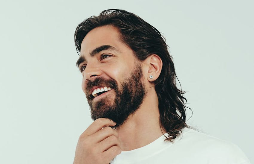 Man smiling and touching his beard