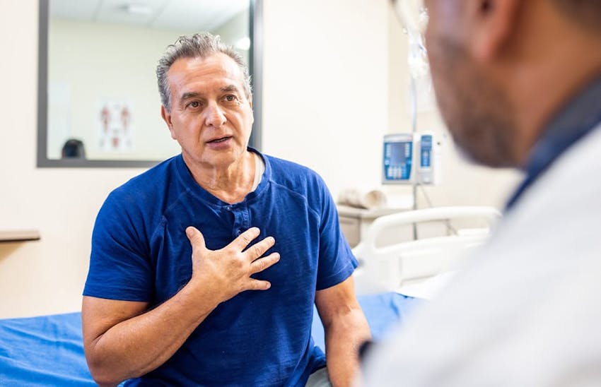 Man holding chest and speaking to doctor