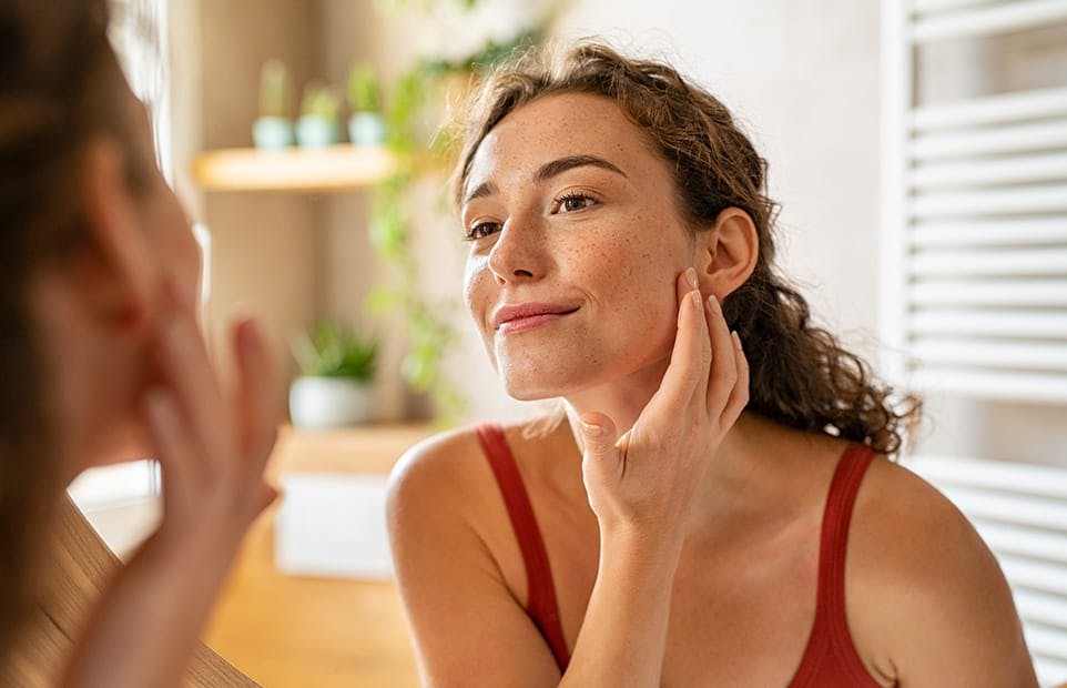 Woman looking at her freckles in the mirror