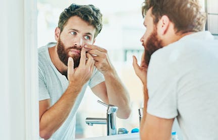 Man examining face in mirror