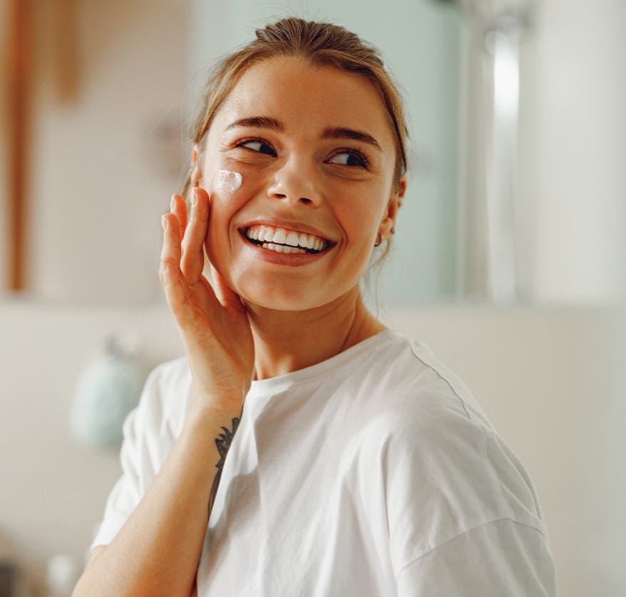 Woman rubbing lotion onto cheek
