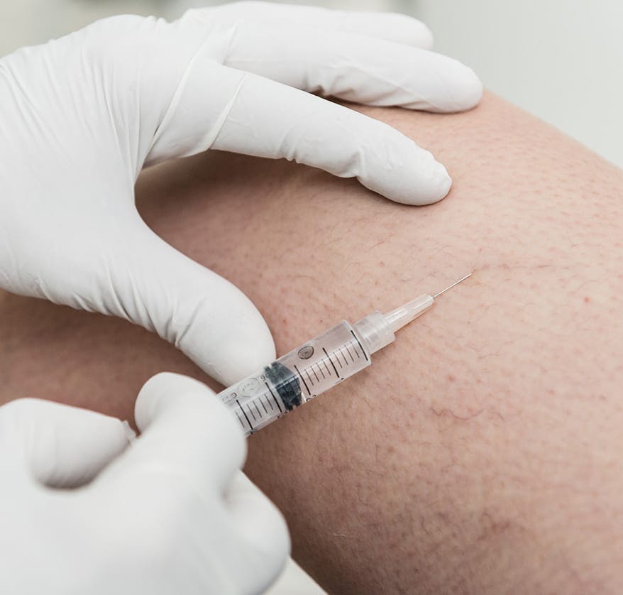 Gloved hands administering injection