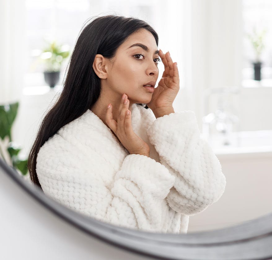 Woman examining eyebrow in mirror