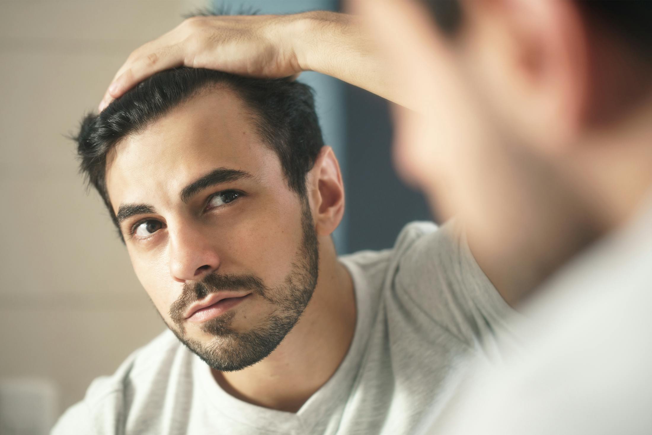 Hair loss patient inspecting hairline in reflection