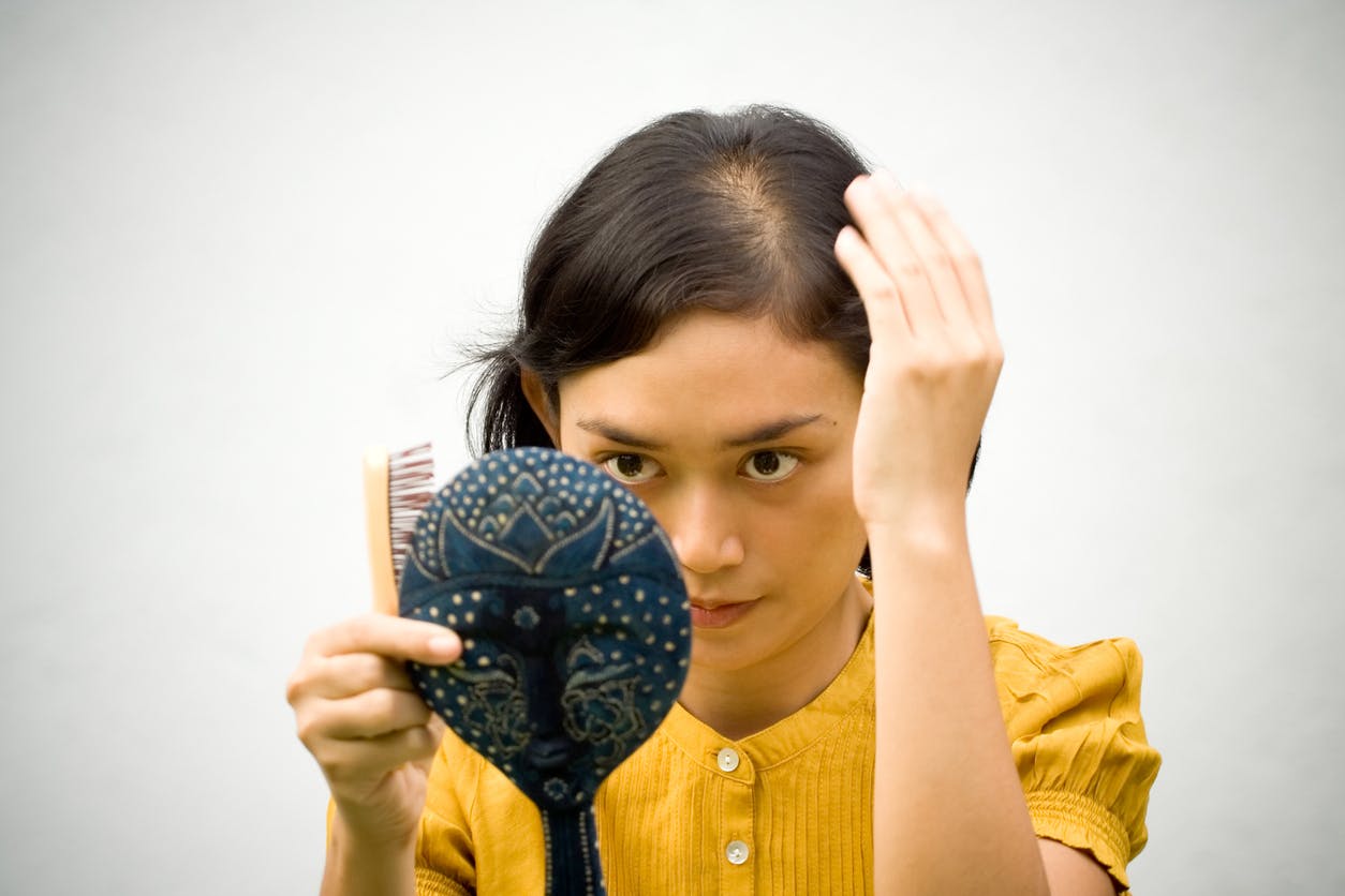 Hair loss patient inspecting hairline in mirror
