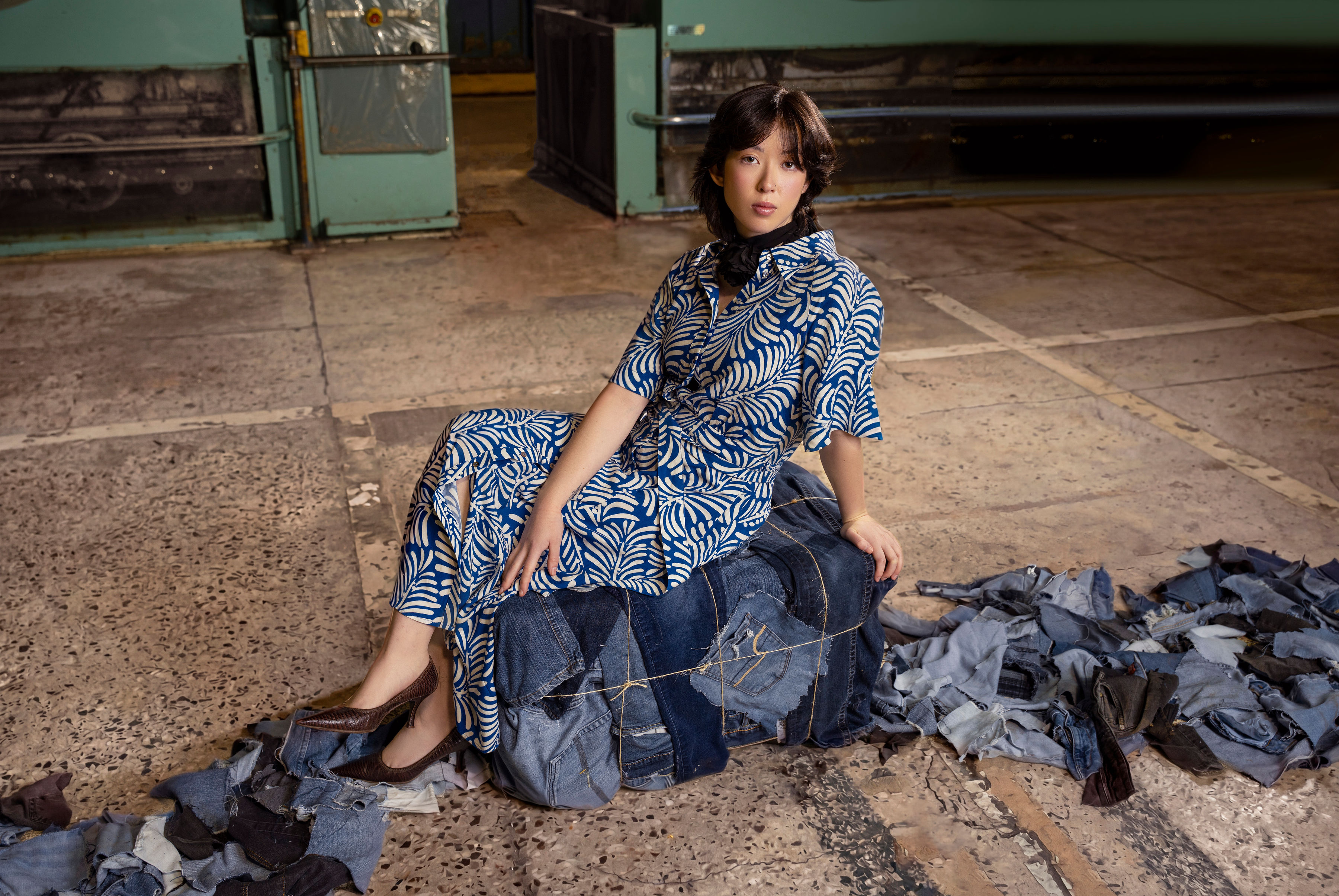 A model sits atop a recycled denim textile bale