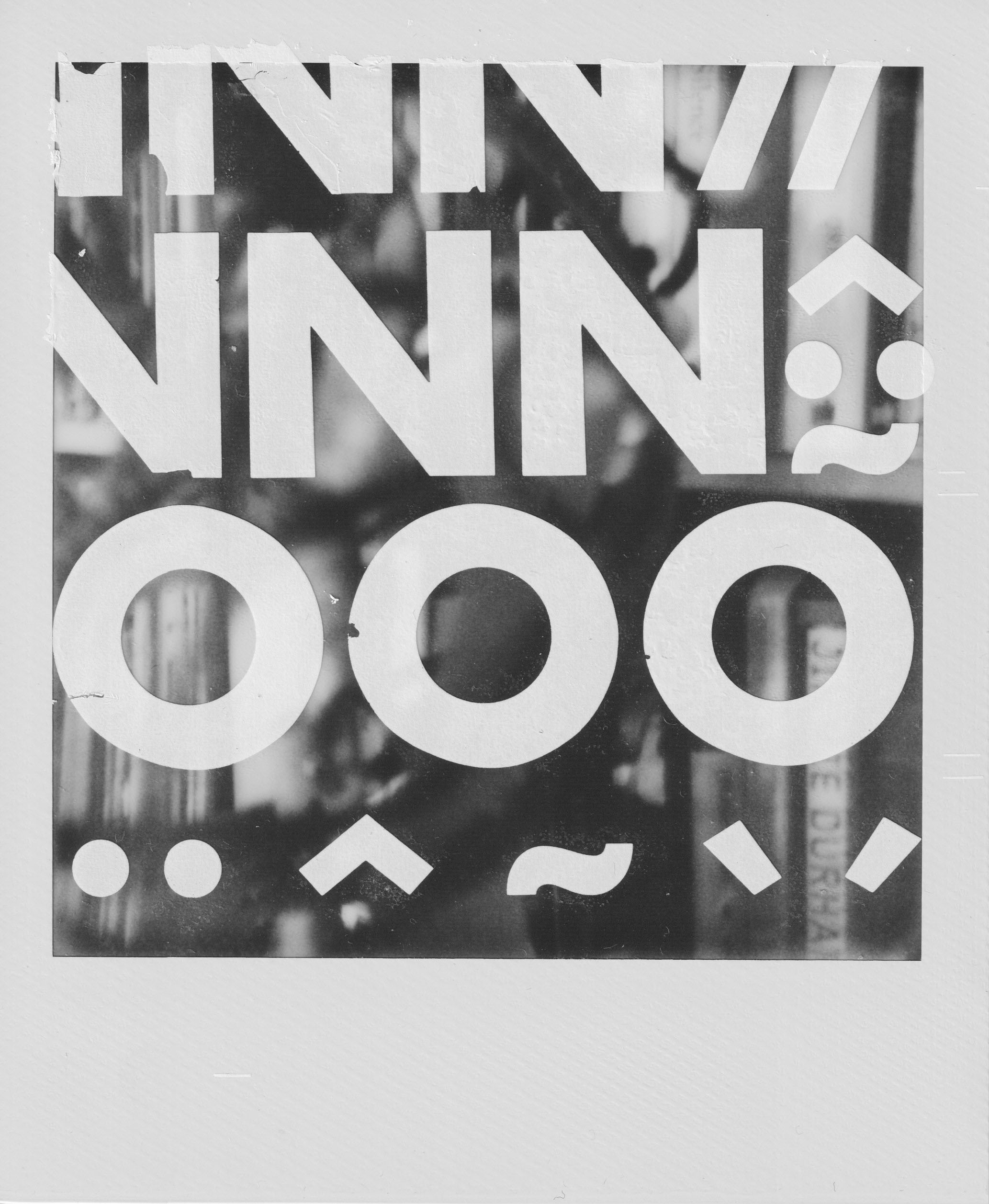 A scanned Polaroid semi-blurry out of focus photograph depicting a book shelf, on top of the Polaroid there are letters transfered spelling NNNOOO and some abstract unctuations.a