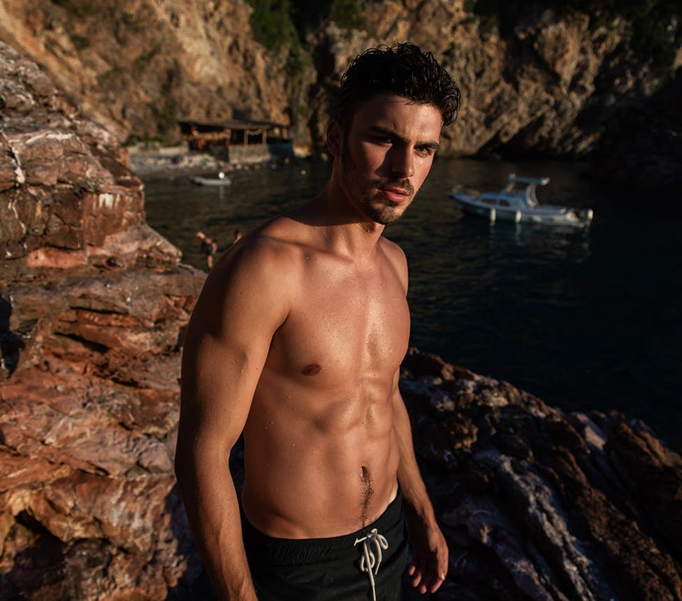 shirtless man standing on rocks