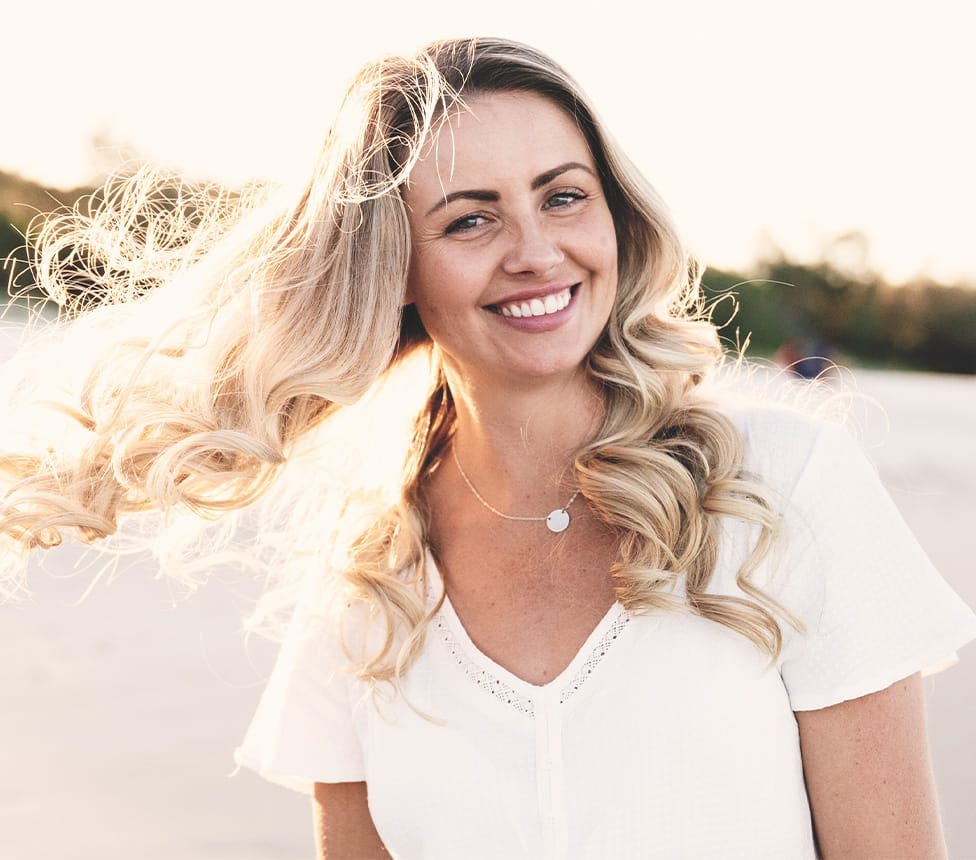 Woman smiling, her long blonde hair blowing in the wind