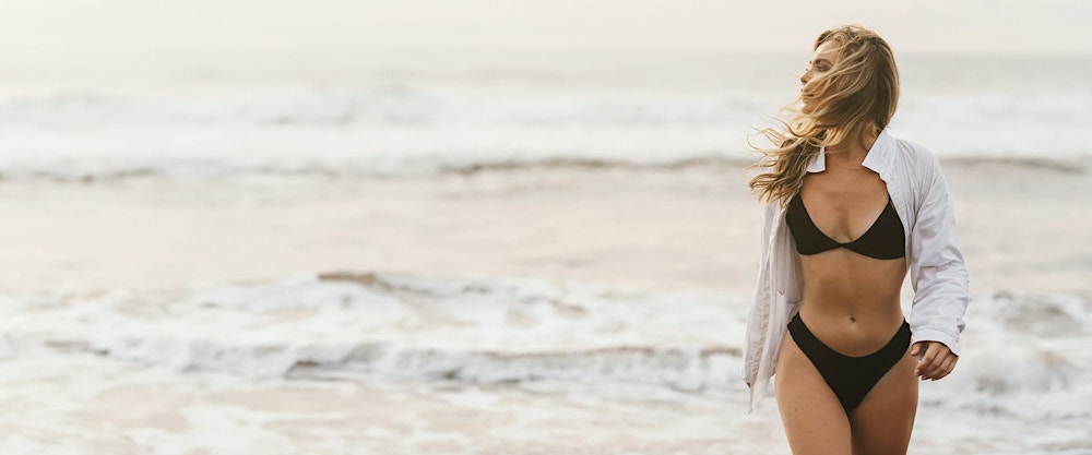 woman in a bikini walking on a beach