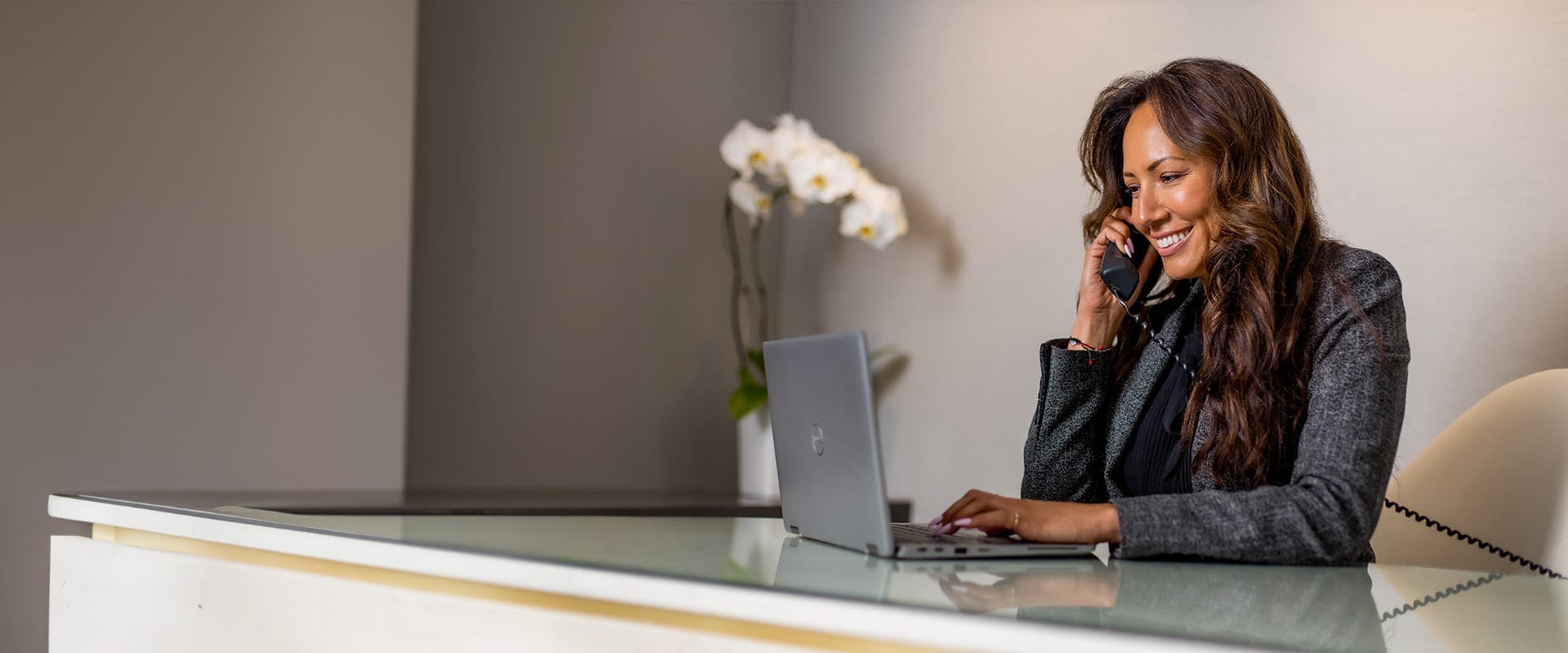Woman on the phone, typing on a laptop