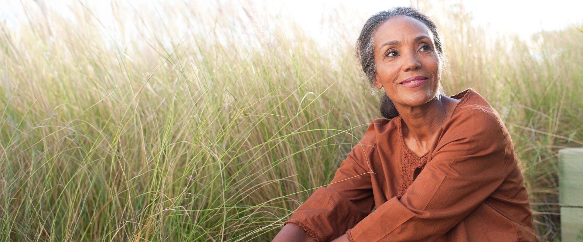 woman sitting in a field wearing a burnt orange shirt