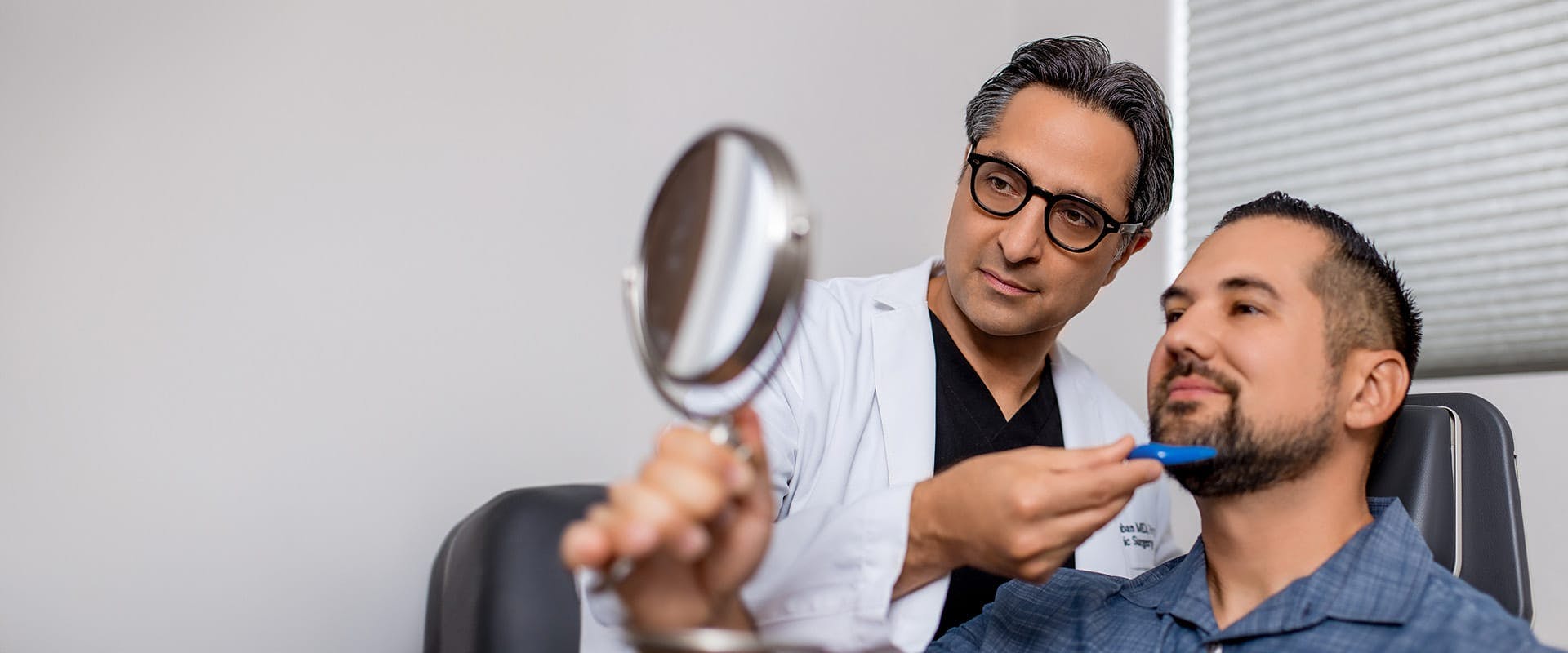 Dr. Rahban showing a patient his results in a hand mirror