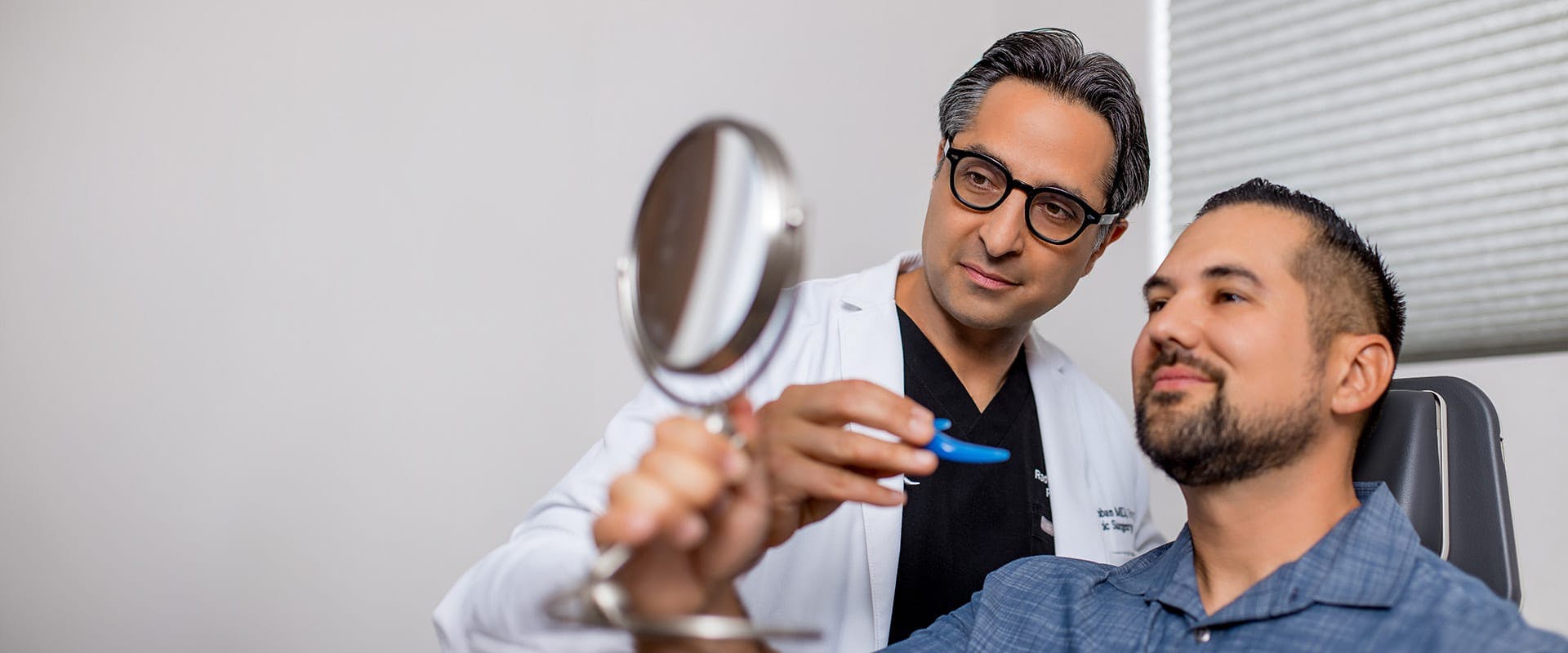Dr. Rahban showing a patient his results in a hand mirror