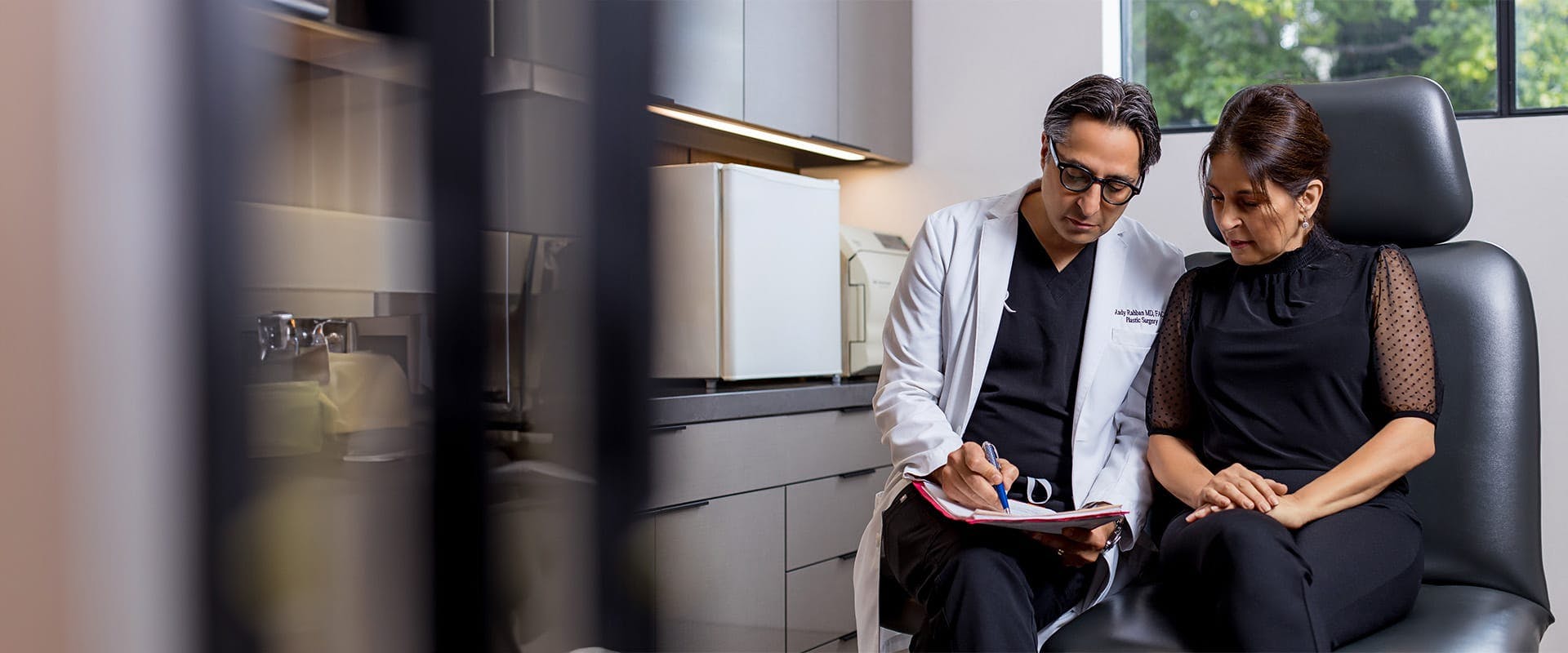 Dr. Rahban writing on a paper with a patient