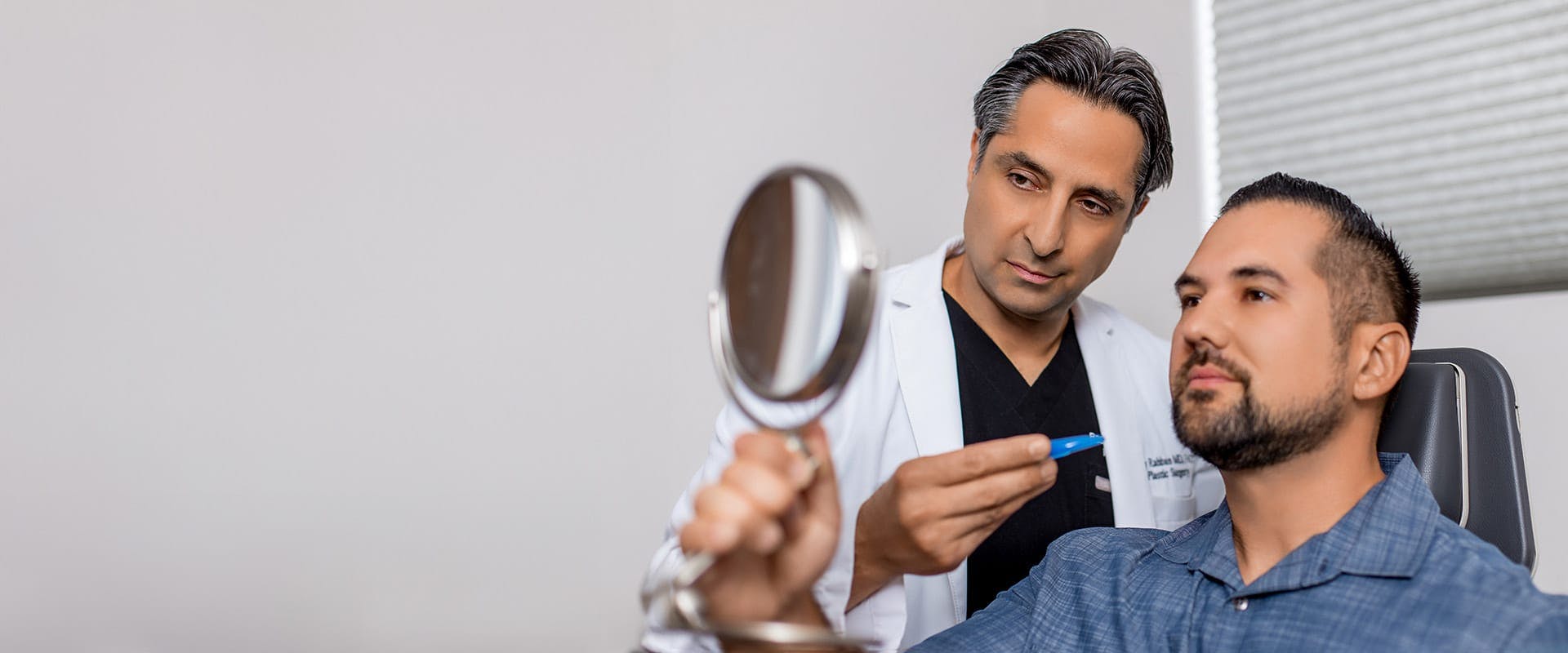Dr. Rahban showing a patient his results in a hand mirror