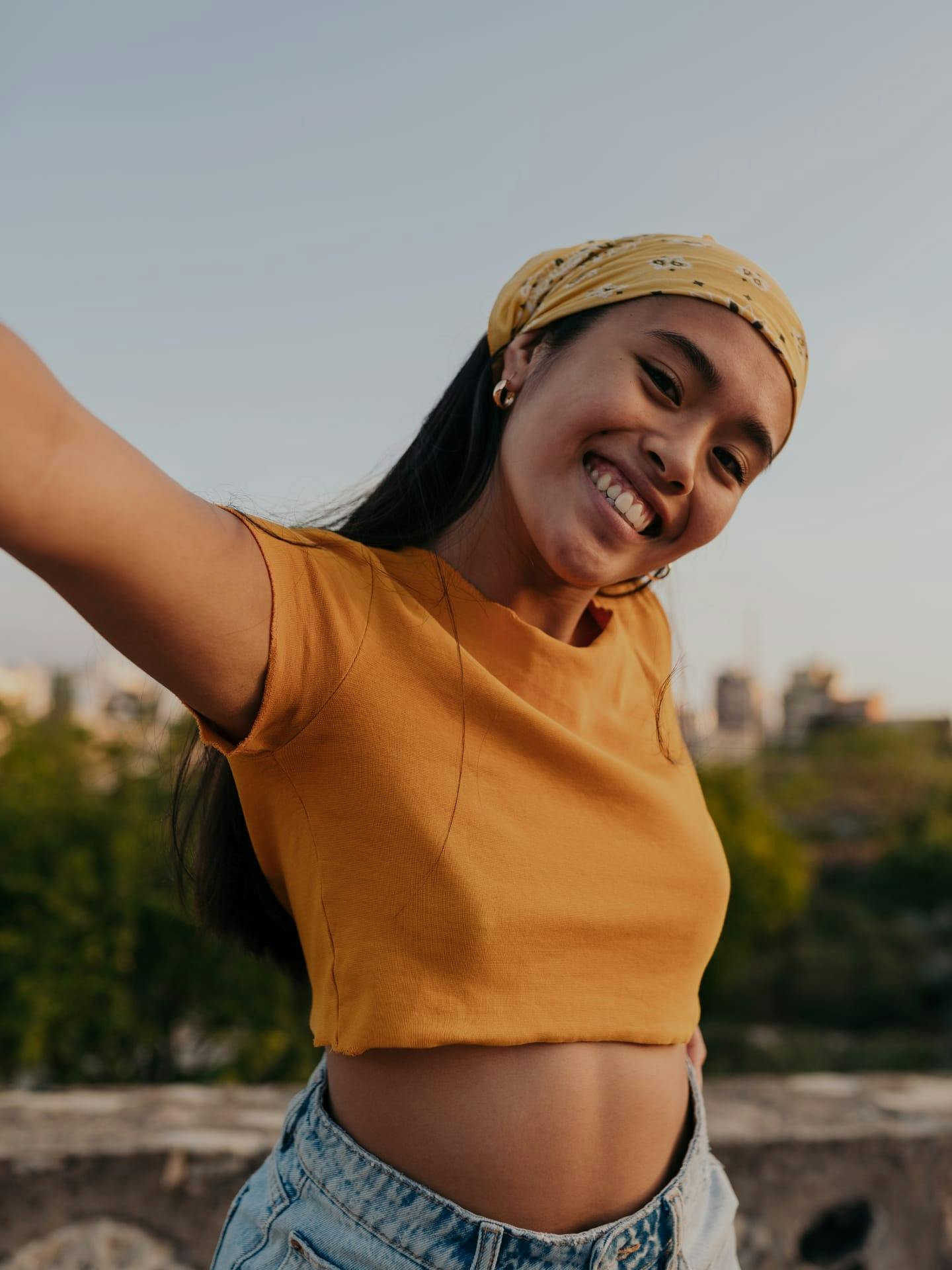 Woman in orange top smiling without glasses