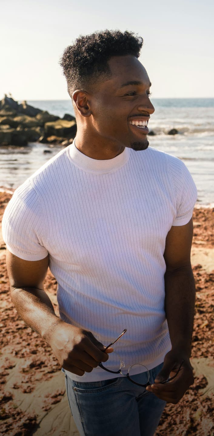 Man in white shirt with glasses off at the beach