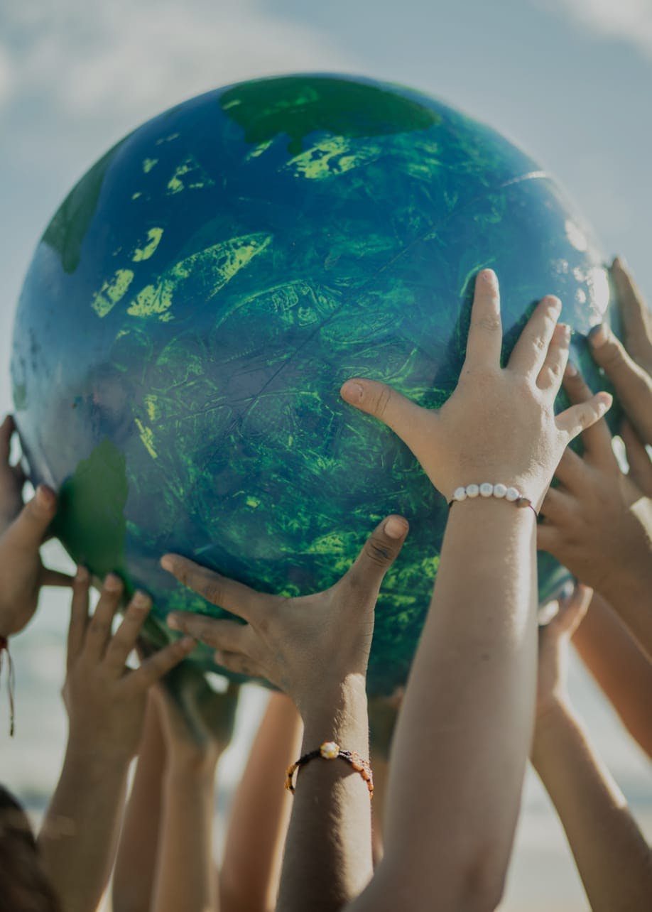 Multiple hands holding up a large globe