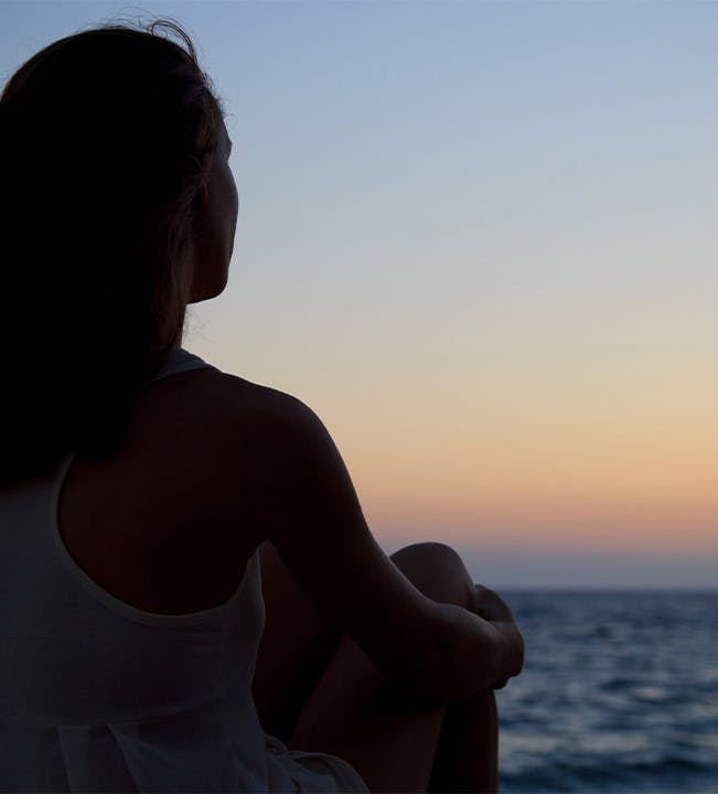 Woman sitting on the beach during sunset