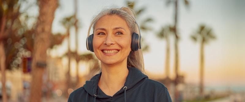 Woman outside with headphones smiling
