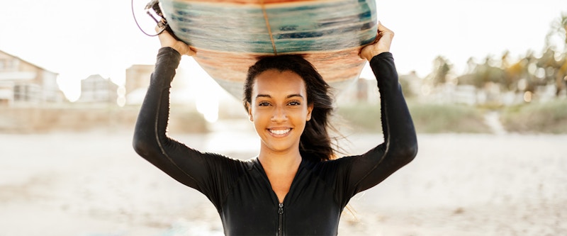 Woman smiling while holding a surfboard
