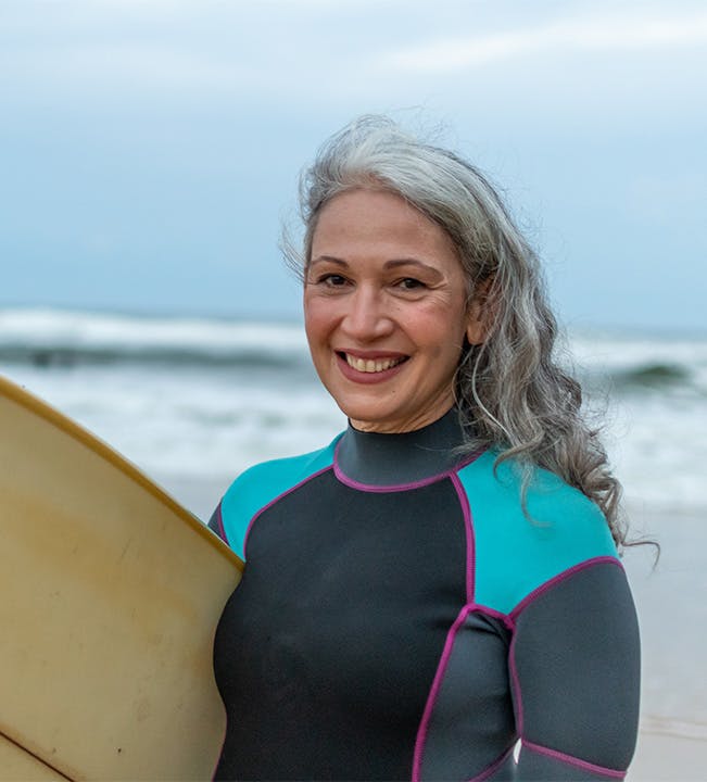 Woman smiling while holding a surfboard