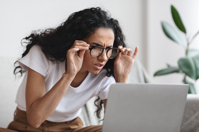 Woman squinting at laptop through glasses