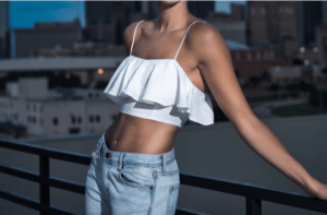 Attractive Slender Woman in a Crop Top and Jeans against a Rail