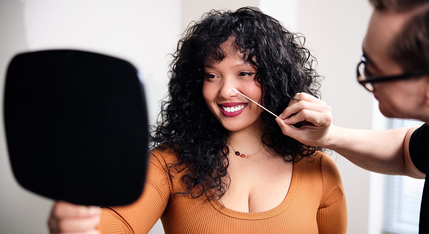 Woman looking in mirror while receiving facial consultation