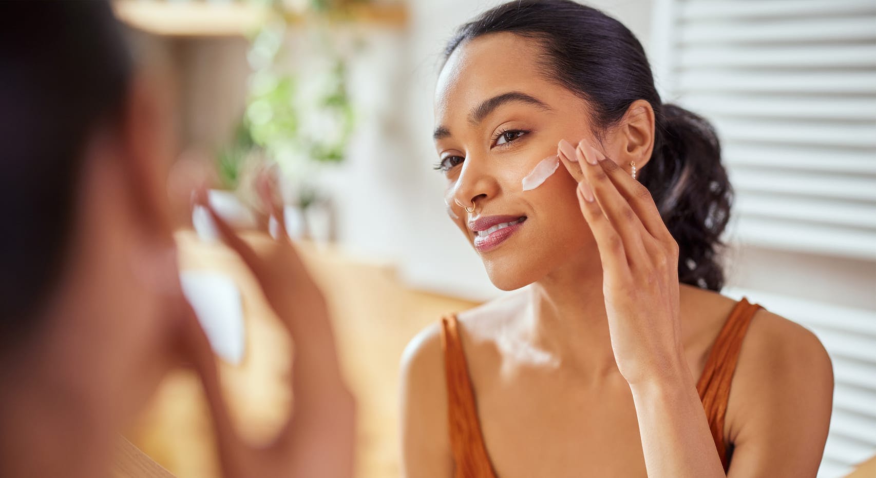 Woman putting cream on her cheek