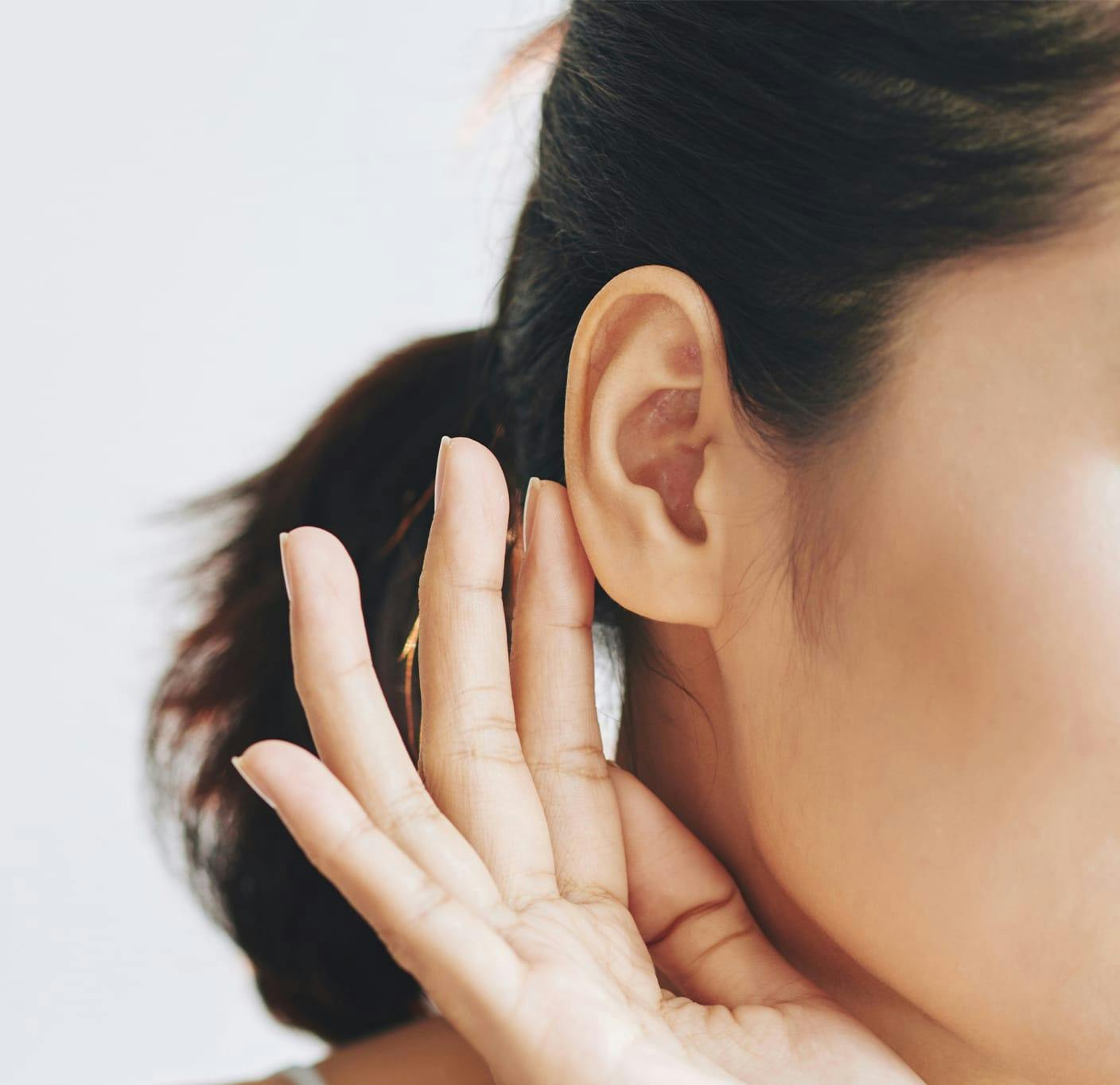 Woman holding hand up to ear to hear better
