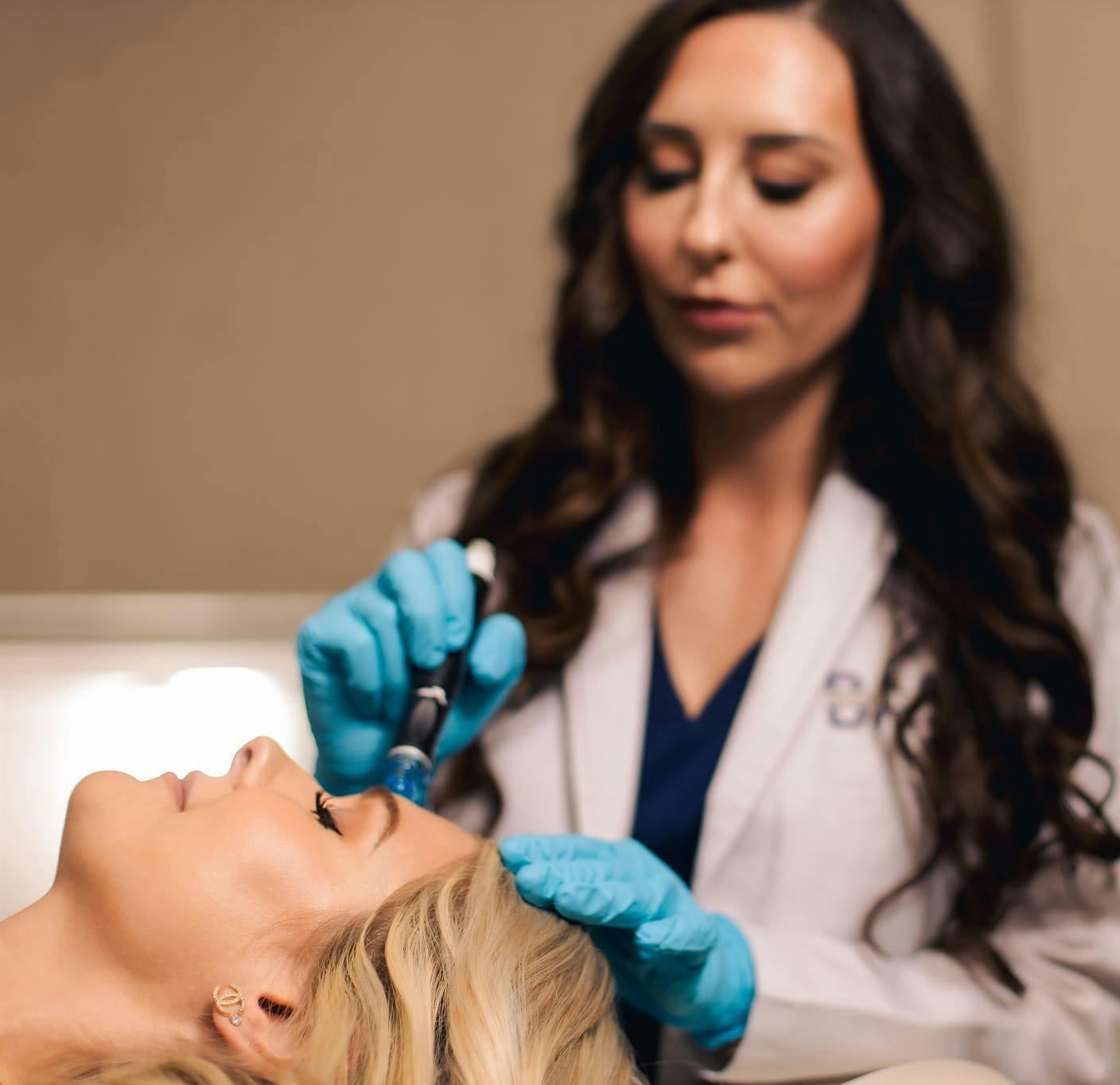 woman doing facial procedure on woman thats laying down