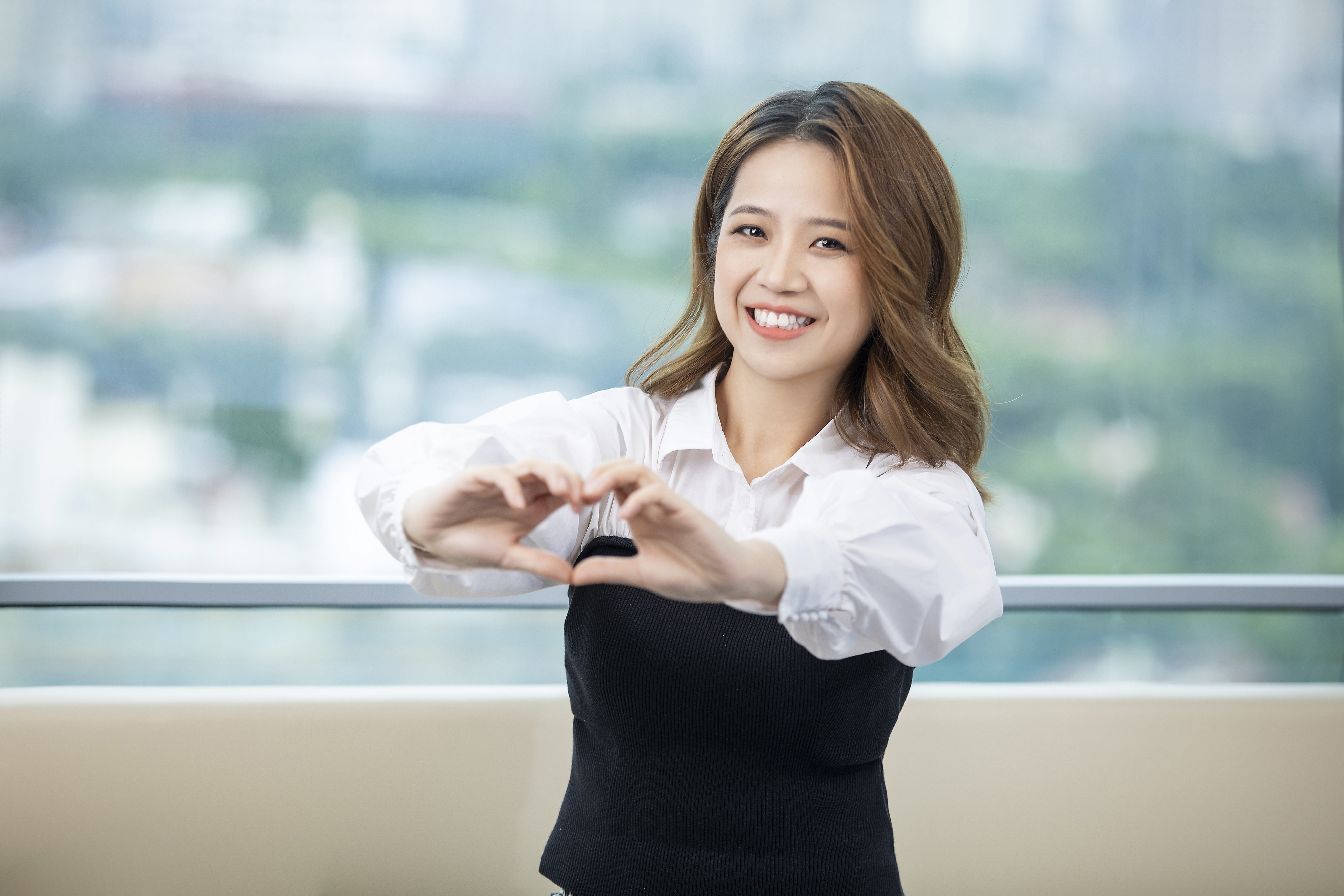 HK - smiling woman giving heart hand gesture to the camera