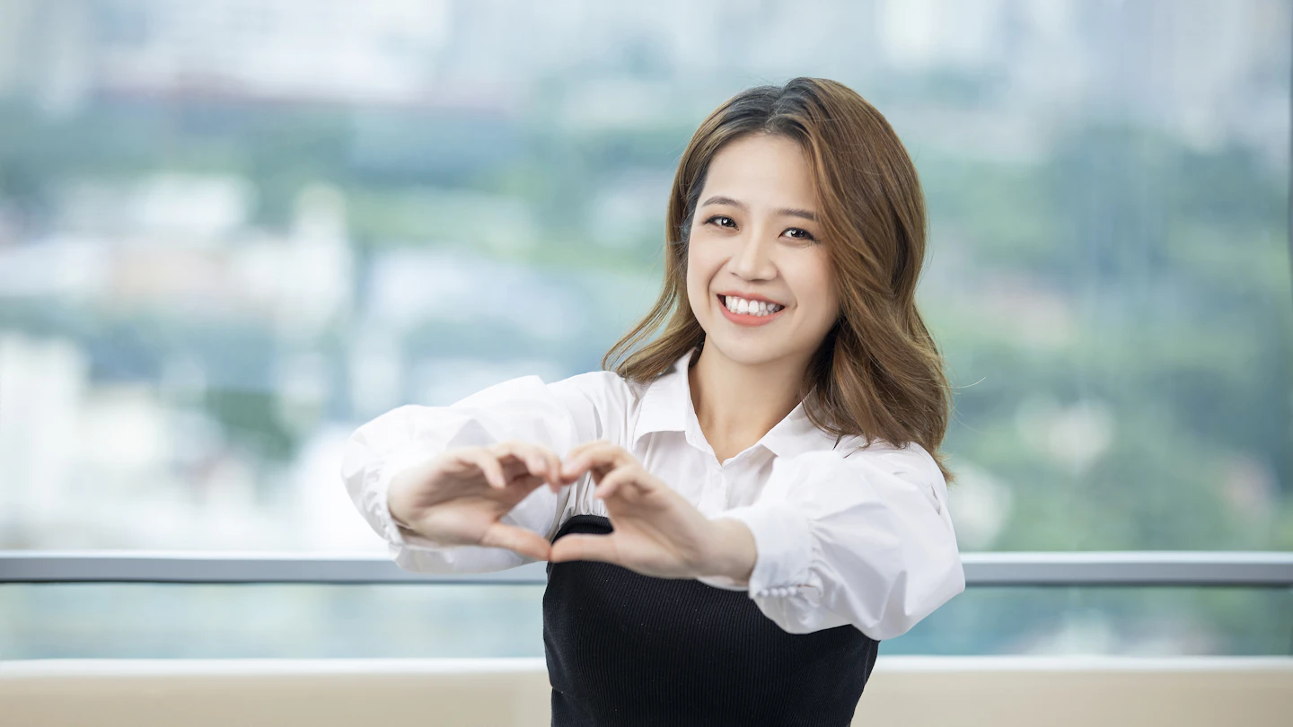 HK - smiling woman giving heart hand gesture to the camera