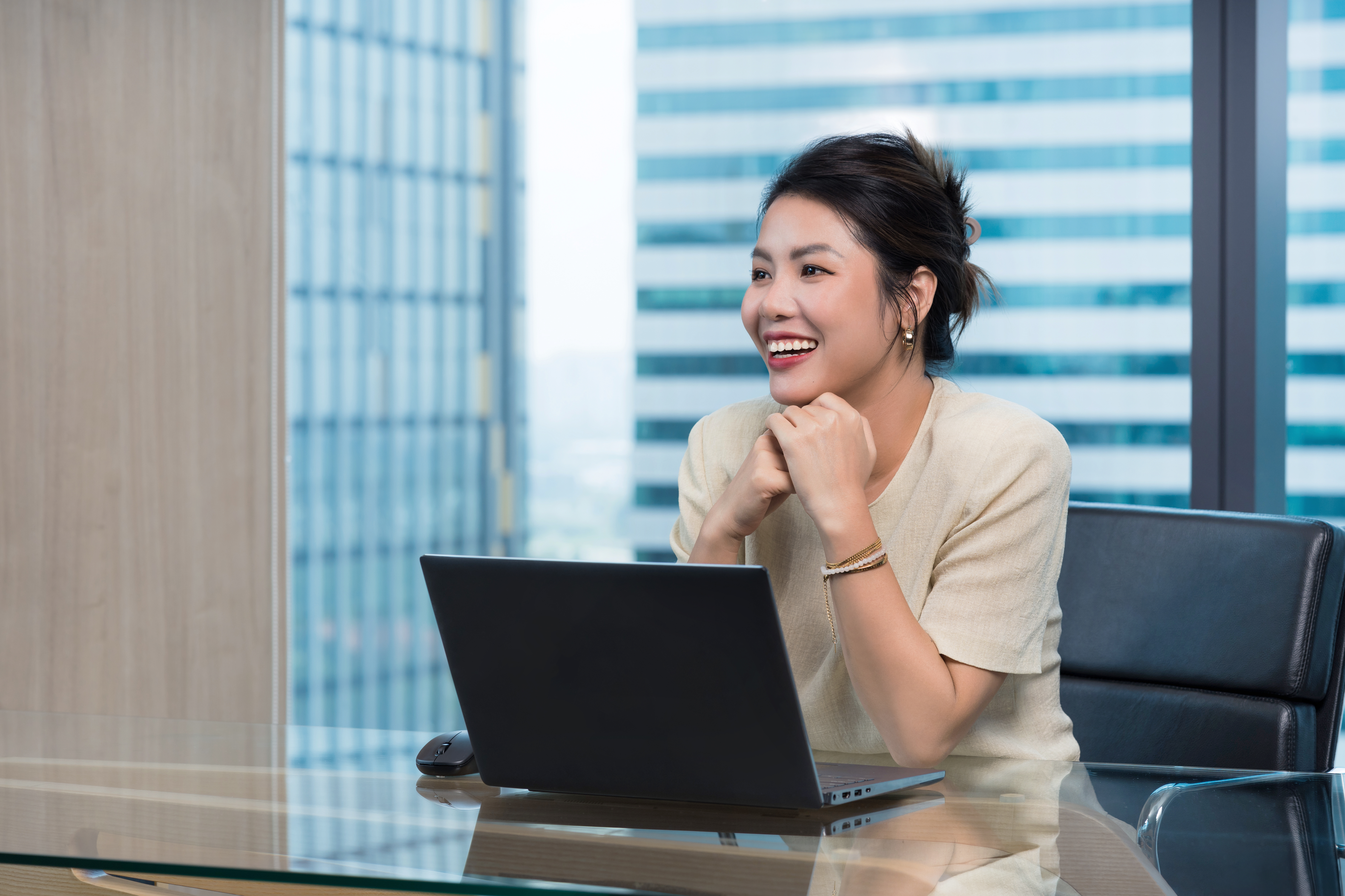 VN - smiling woman sitting at a desk in front of a laptop