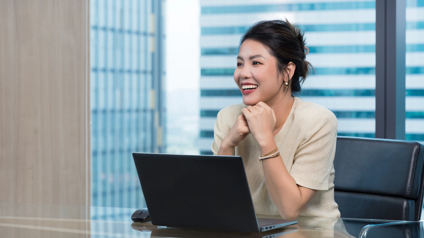 VN - smiling woman sitting at a desk in front of a laptop