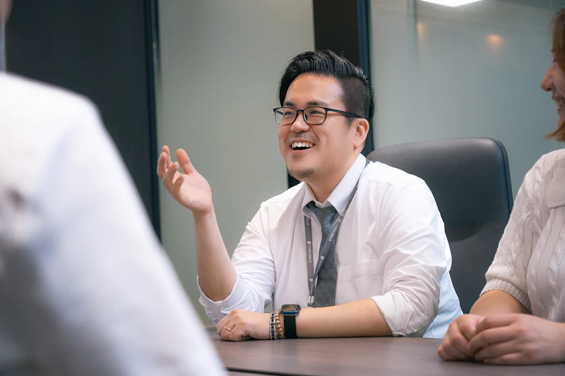KR - smiling man talking to colleagues across a desk