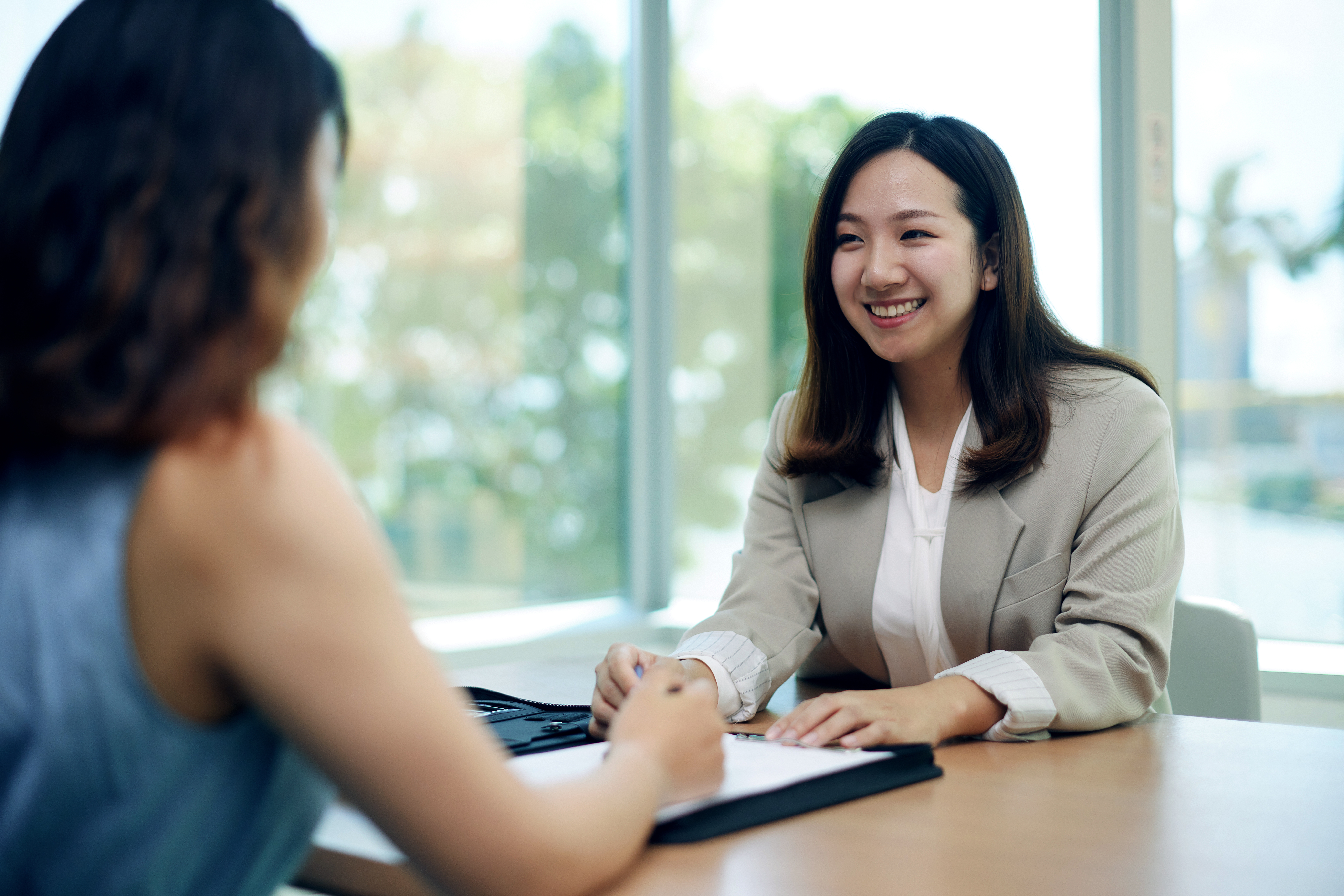 HK - woman smiling at colleague across a work desk