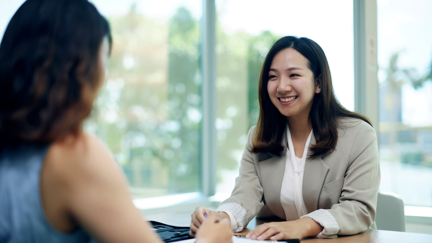 HK - woman smiling at colleague across a work desk
