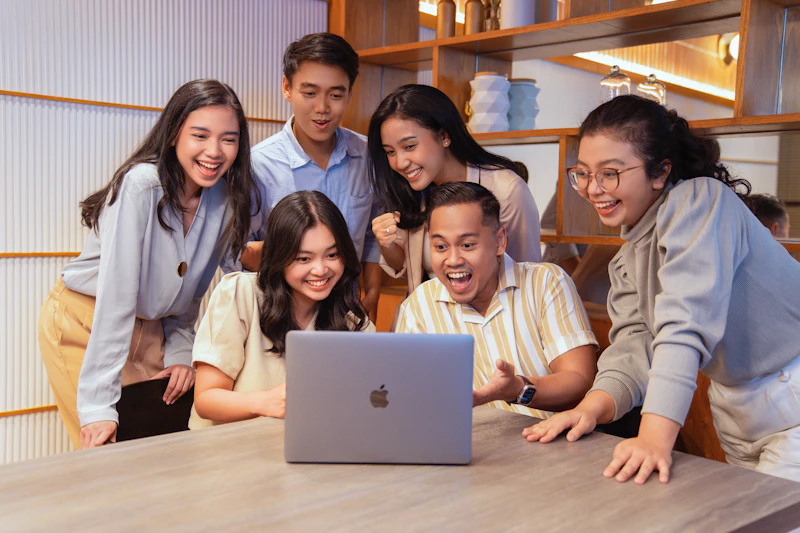 A team of colleagues looking at a laptop on a desk
