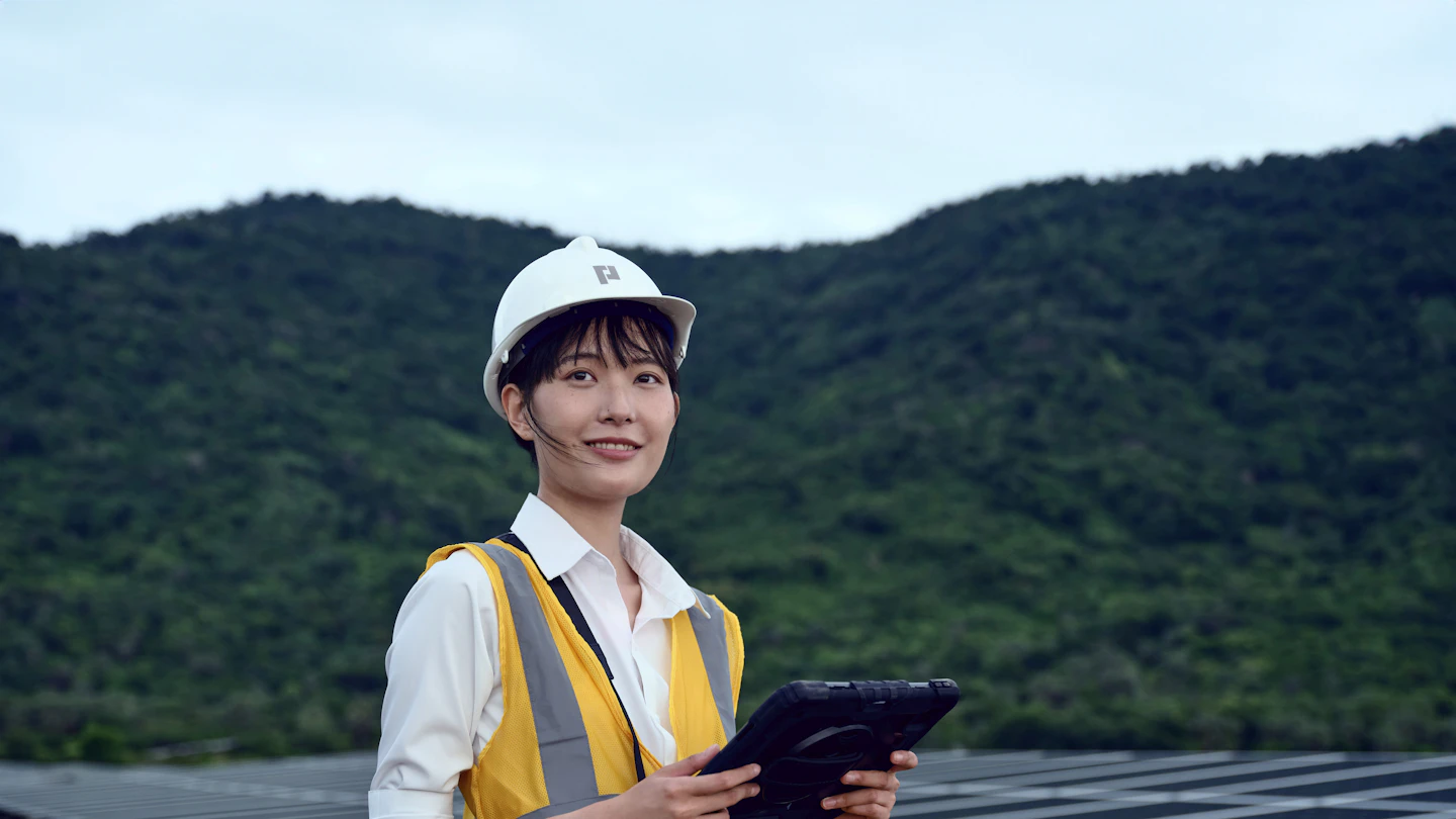 Flexible Workforce Solutions for Organisations That Need to Move Quickly and Compliantly Contract worker in hi-vis vest and hard hat using a tablet at a solar farm
