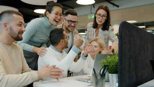 work culture Diverse team celebrating success at office desk.