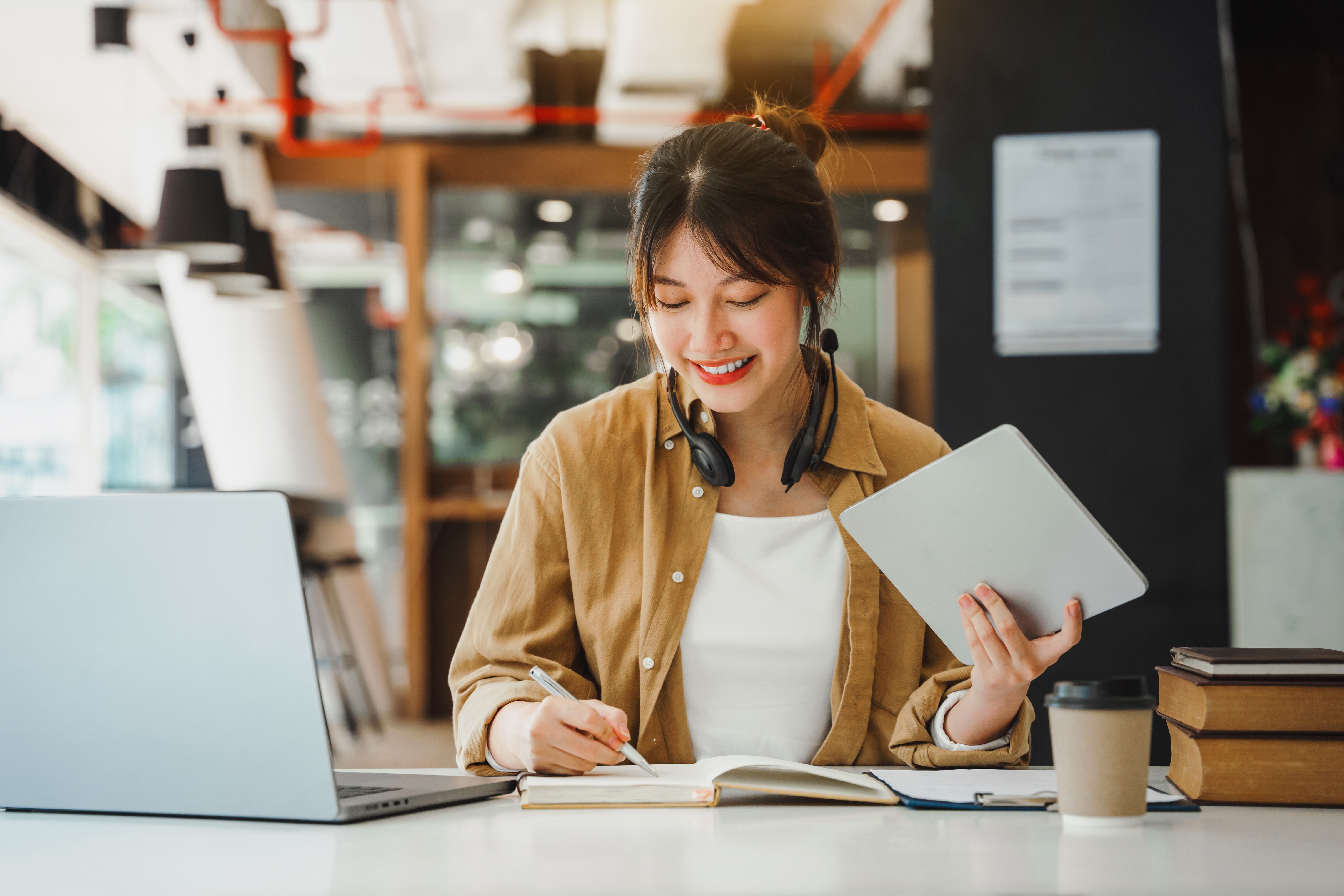 HR consultant taking notes beside a tablet in a bright workspace