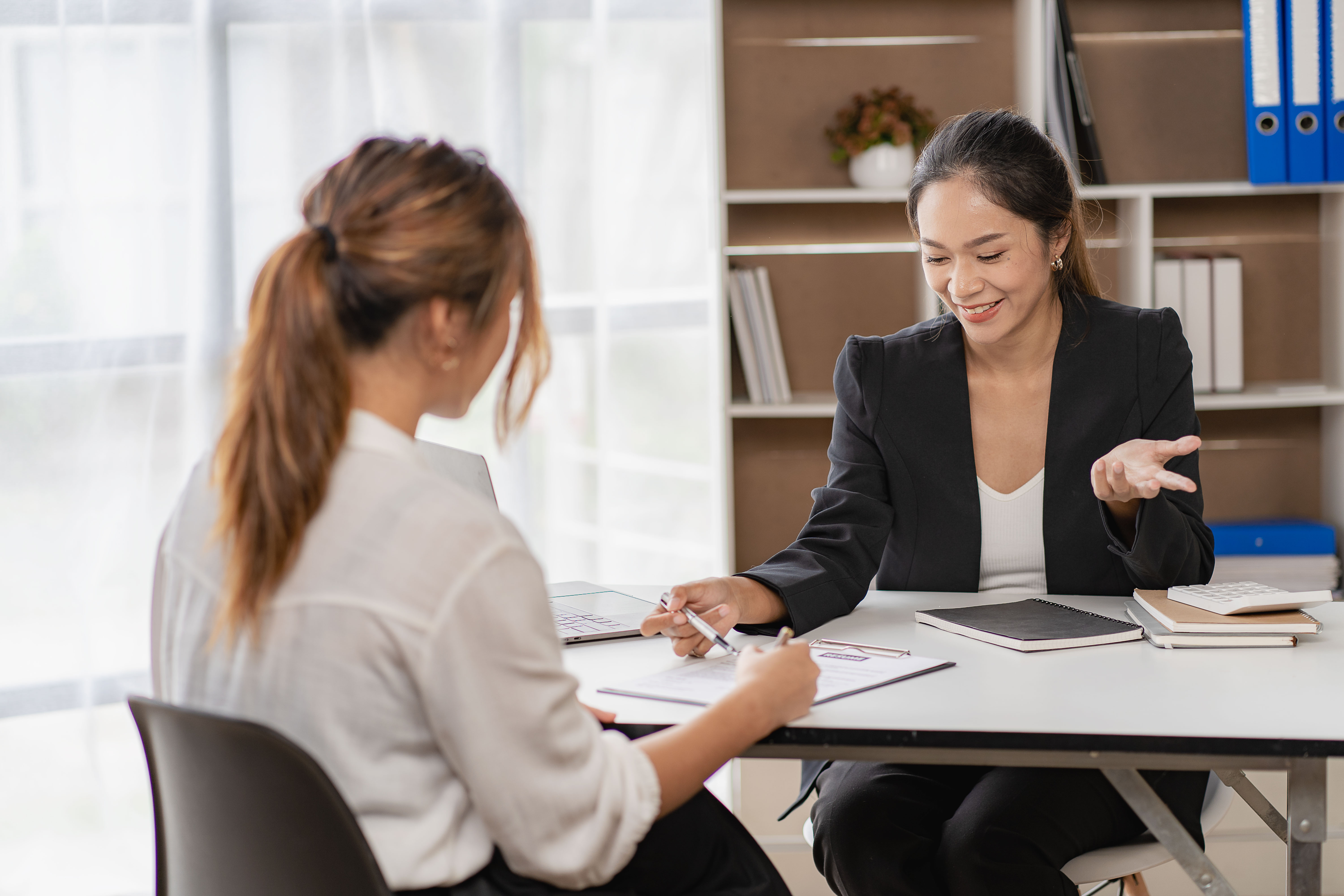 HR adviser walking a client through a document at a desk